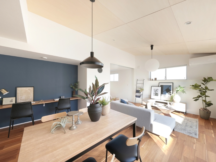 落ち着いたブルーのアクセントクロスが印象的なモダンなリビング。ダイニングチェアの黒い細い脚が、空間をスタイリッシュに引き締めている。