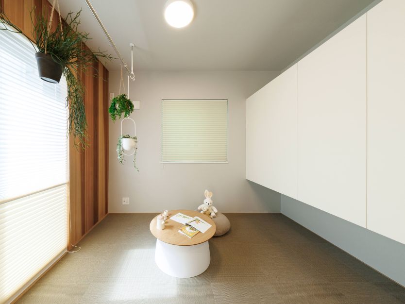 カーペット敷きの小部屋（ヌック）に置かれたローテーブルと、壁面の白い造り付け収納